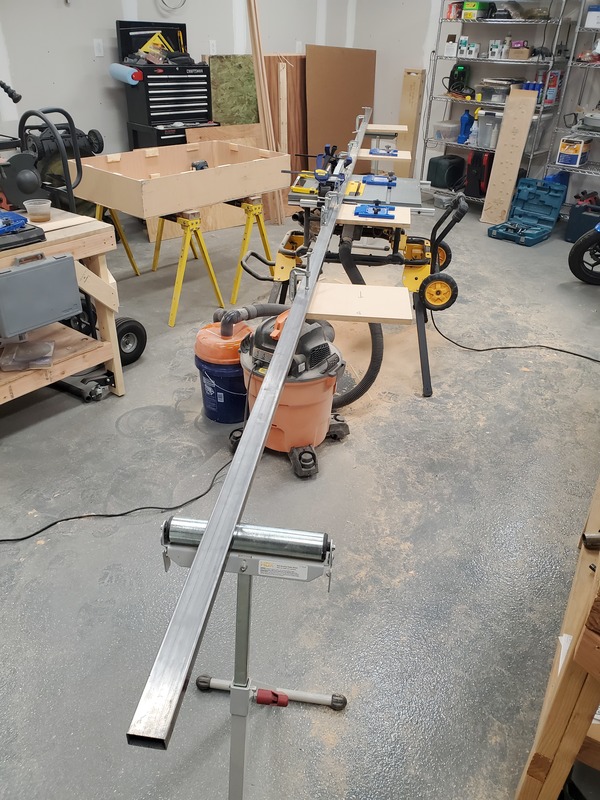 View of a contractor table saw with a 20 foot long fence,
supported by roller stands