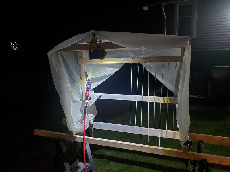 Night-time photograph of a rickety-looking structure covered in
plastic, with an LED worklight