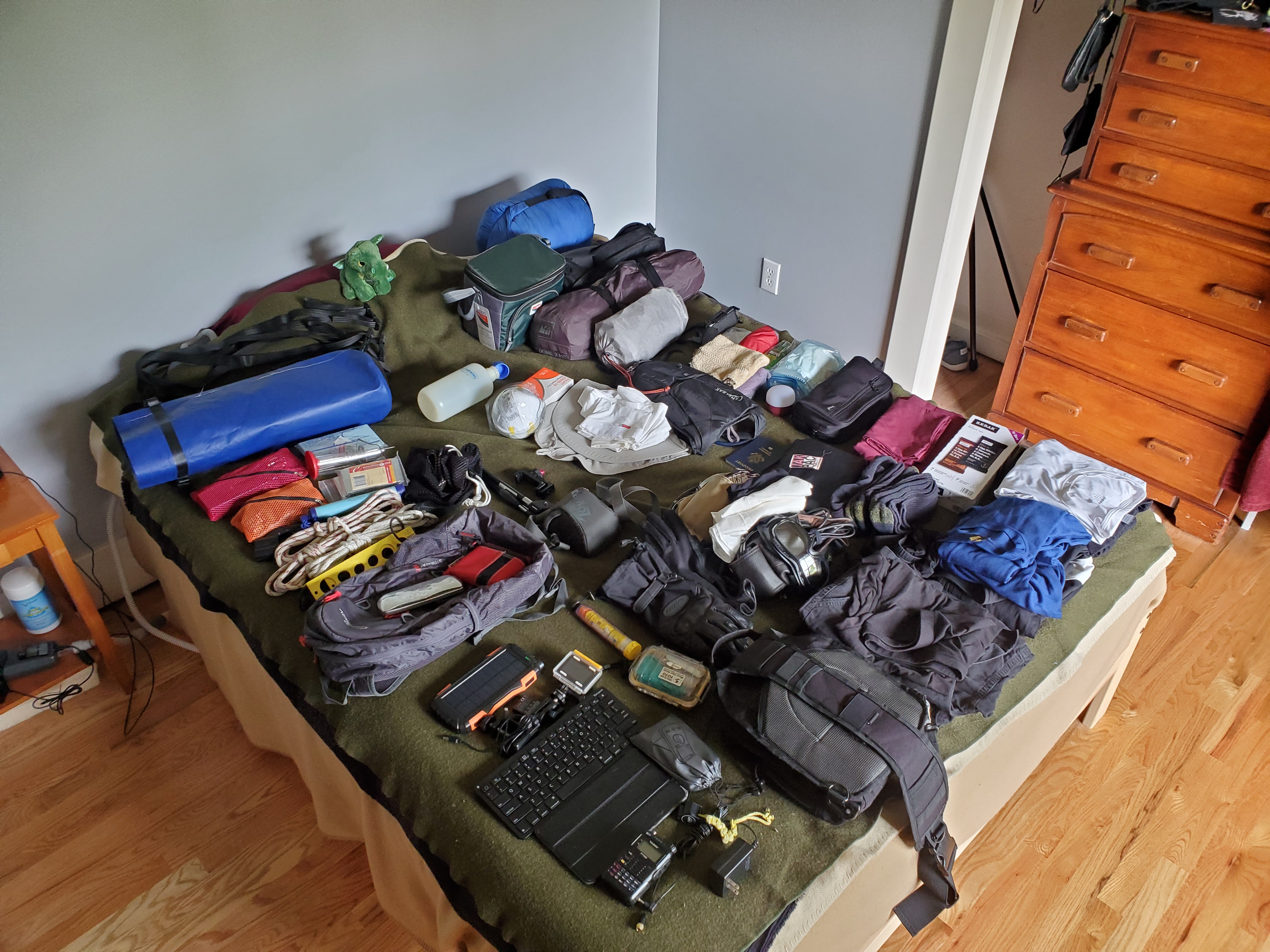 Photo of a
queen size bed covered in stuff: clothing, but also a pair of old-timey
WWI Ace flying helmets, radios, a keyboard, and mysterious bags full of
who-knows-what.  It's a lot of stuff.