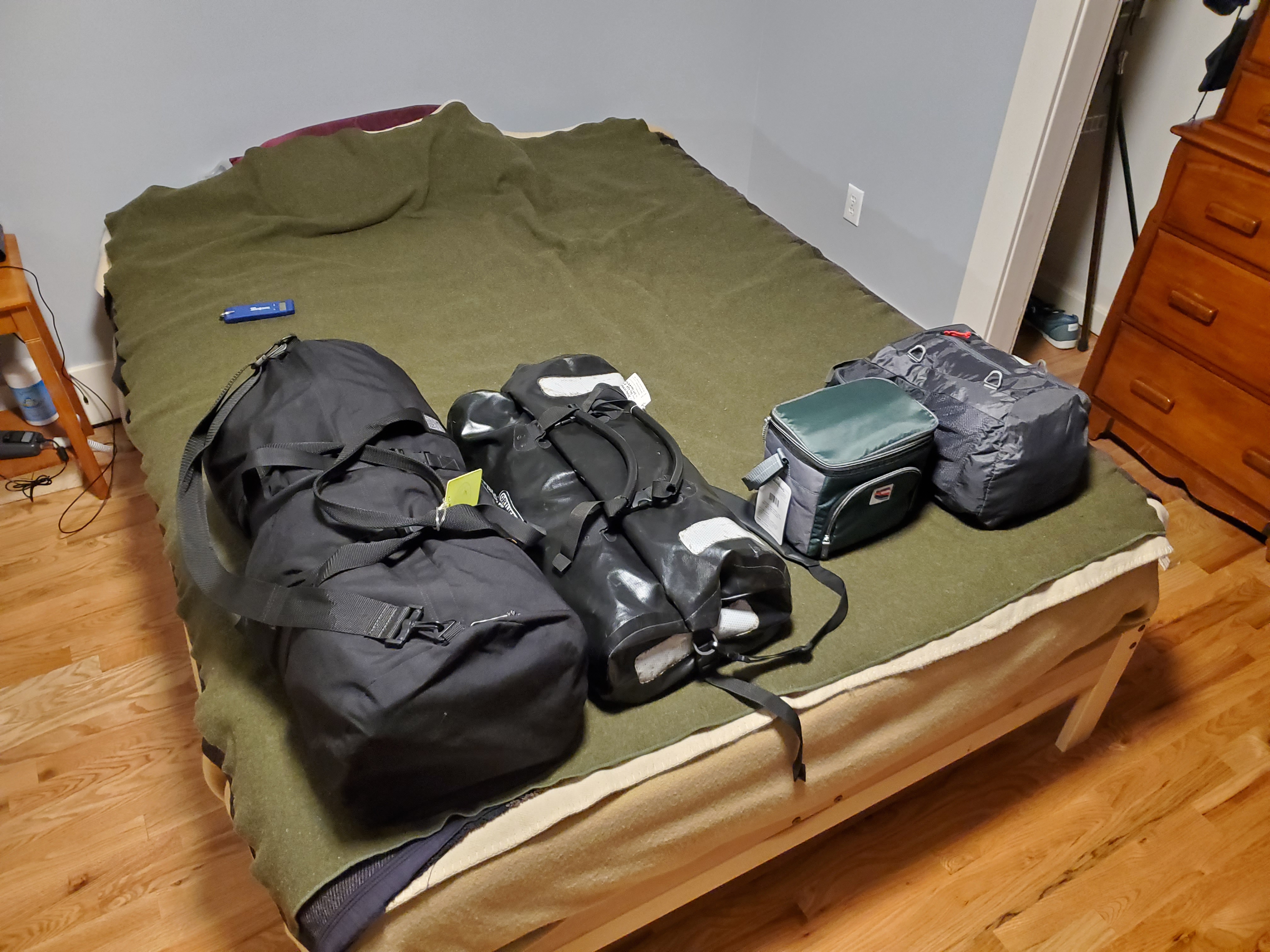 Photo of four
well-stuffed bags sitting neatly in a row: two large black duffel bags,
a small backpack, and a little six-pack sized cooler bag